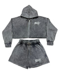 A two-piece dark gray acid-wash fleece set consisting of a cropped zip-up hoodie and matching shorts, both featuring a white 'WEXIST' logo on the chest, laid flat on a white background.