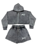 A two-piece dark gray acid-wash fleece set consisting of a cropped zip-up hoodie and matching shorts, both featuring a white 'WEXIST' logo on the chest, laid flat on a white background.